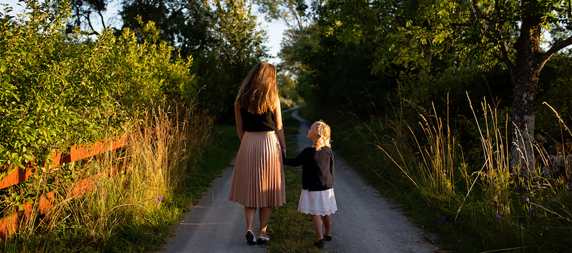 Image of two girls standing on a dirt path surrounded by trees