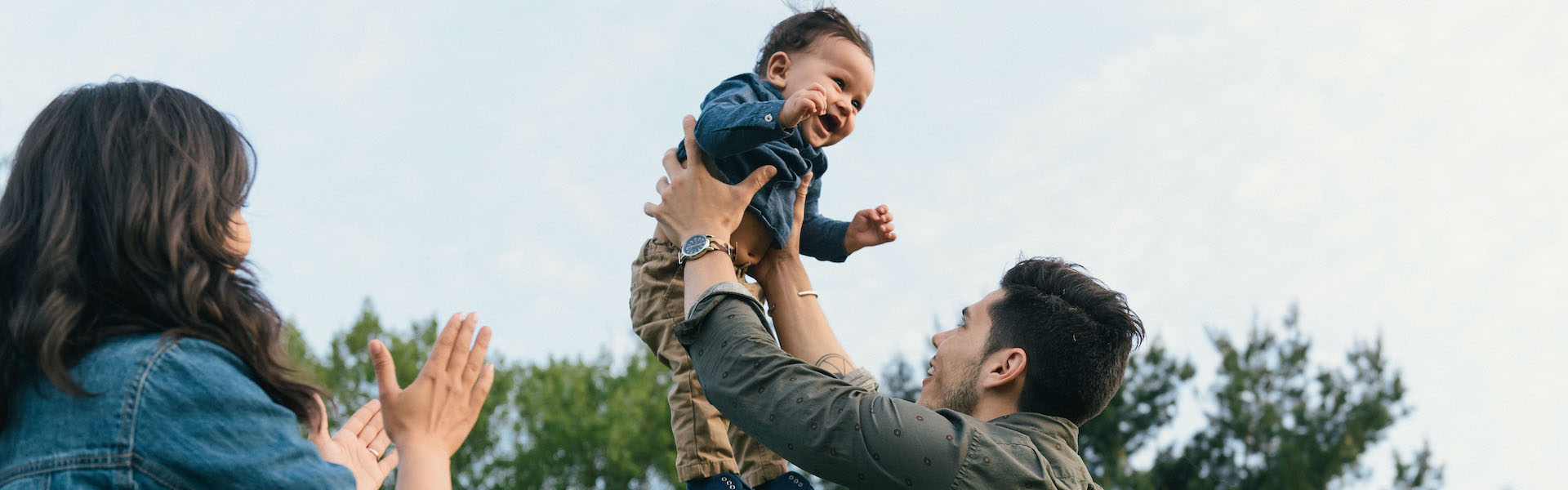 Dad raising child in air with mother clapping